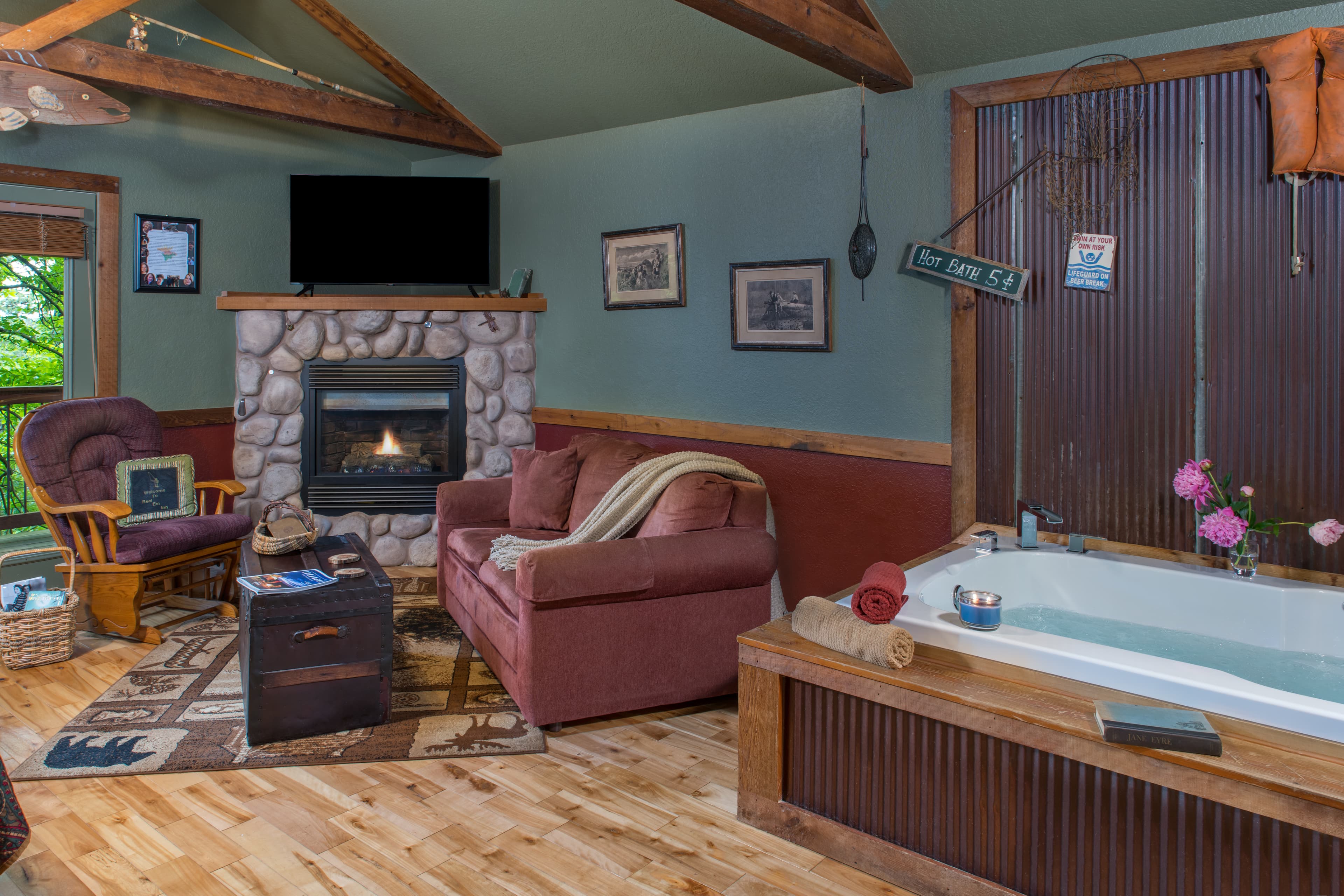 Cozy living area featuring a stone fireplace, plush seating, and a luxurious bathtub.