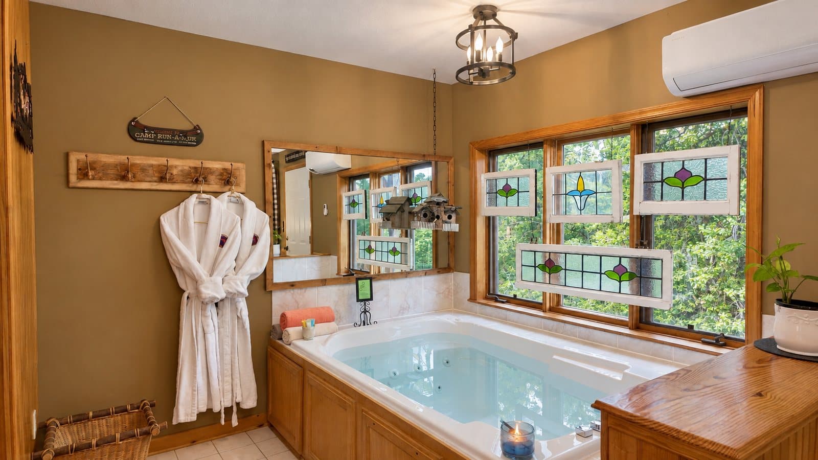 A cozy bathroom featuring a jacuzzi, wooden accents, stained glass windows, and a white robe hanging on the wall.