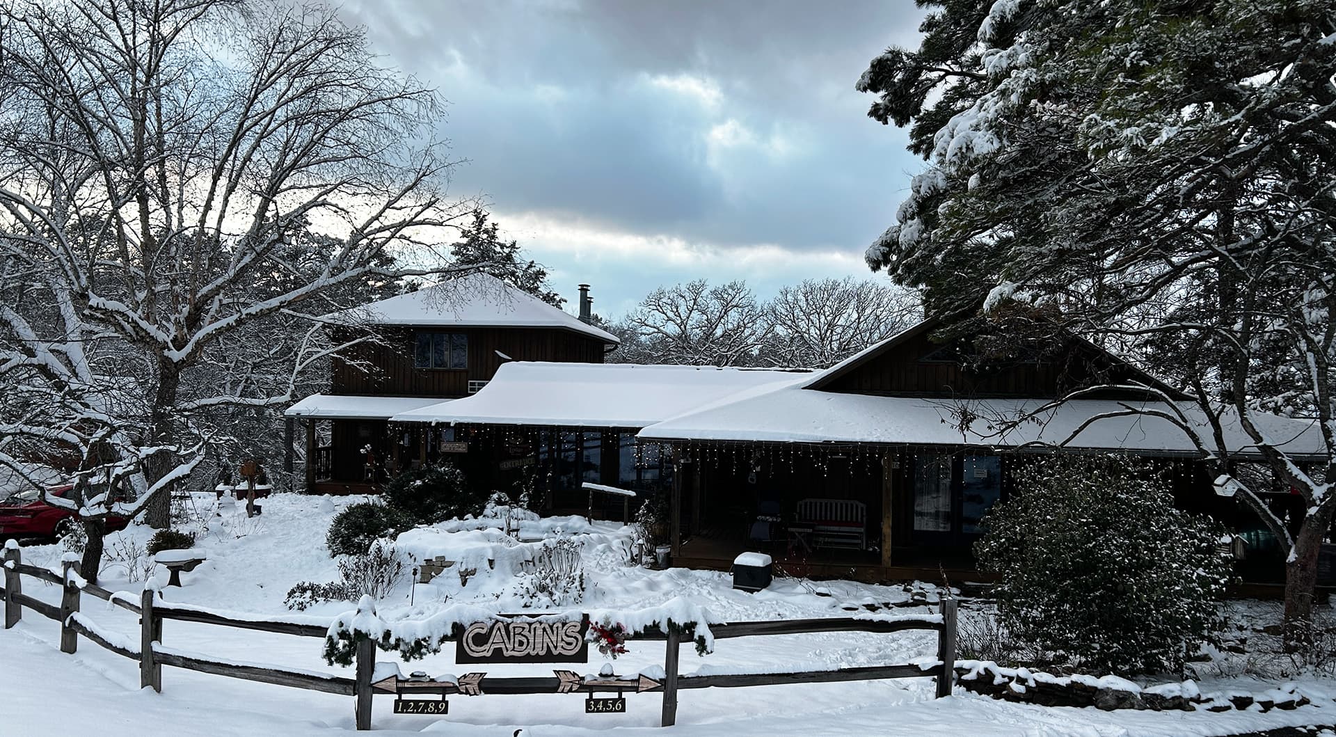 A cozy cabin covered in snow, with a sign reading "CABINS" and surrounding winter scenery.